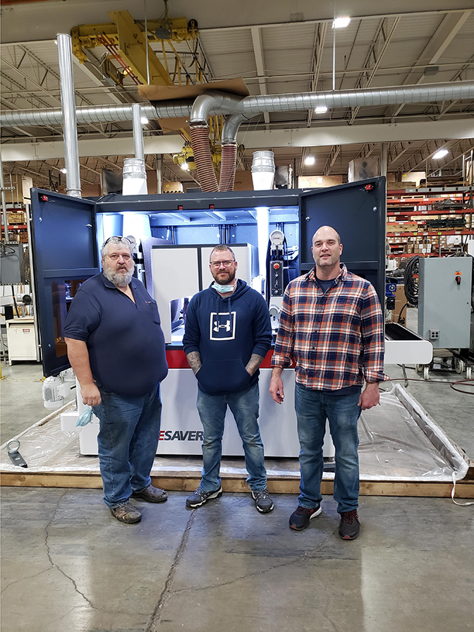 Three Timesavers employees in front of Timesavers machinery